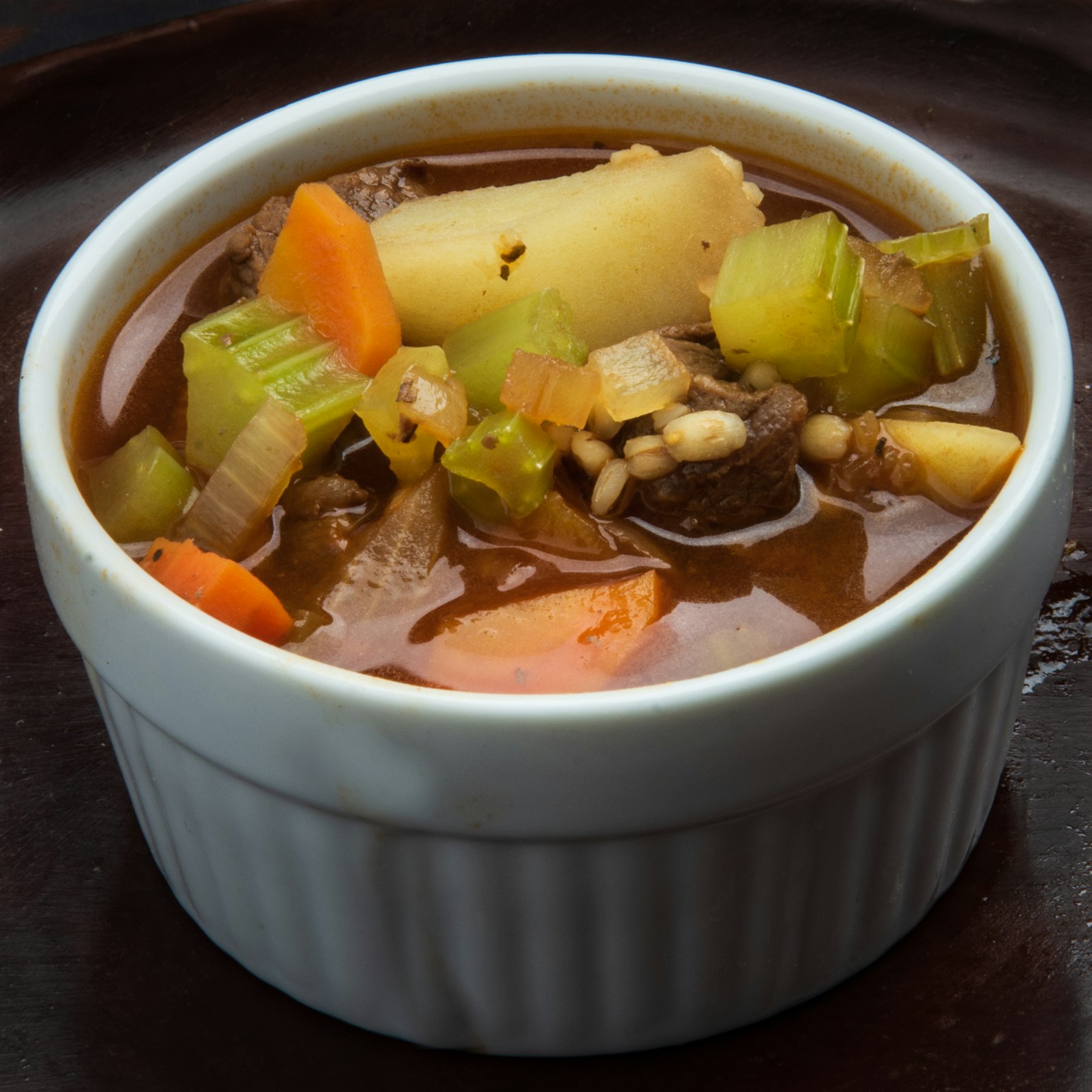 A steaming bowl of vegetable lentil soup with carrots and potatoes