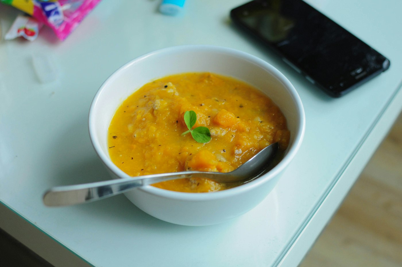 A bright bowl of orange sweet potato puree with a spoon