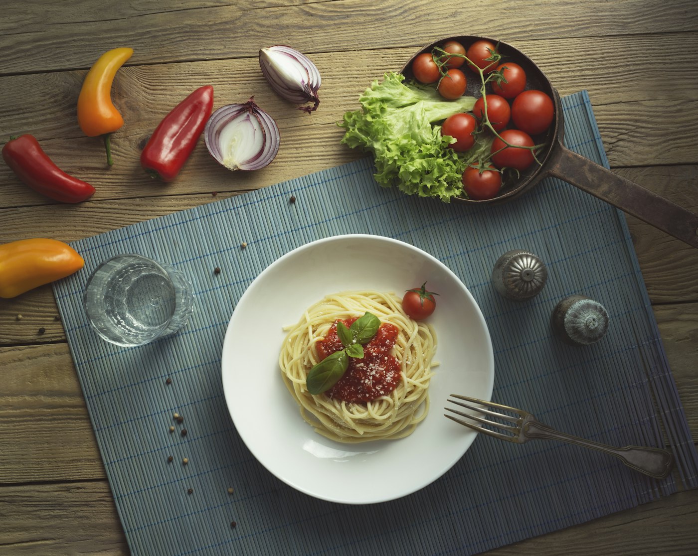 A plate of pasta with cherry tomatoes and fresh vegetables, seen from above