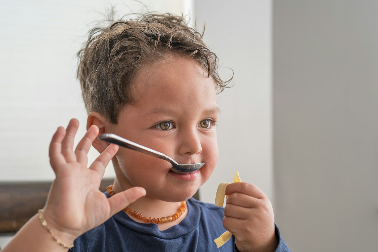 A toddler happily eating with a spoon